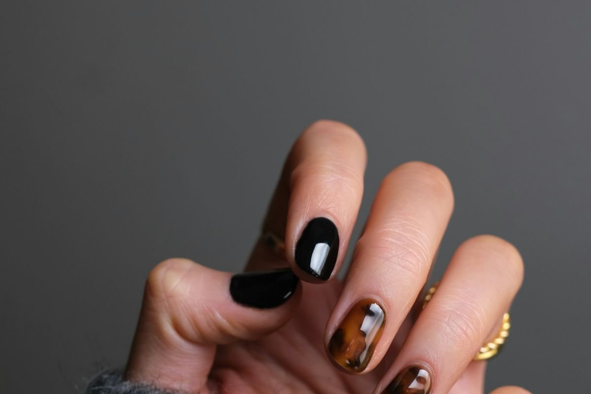 Manicura terminada en esmalte oscuro con diseño de uñas